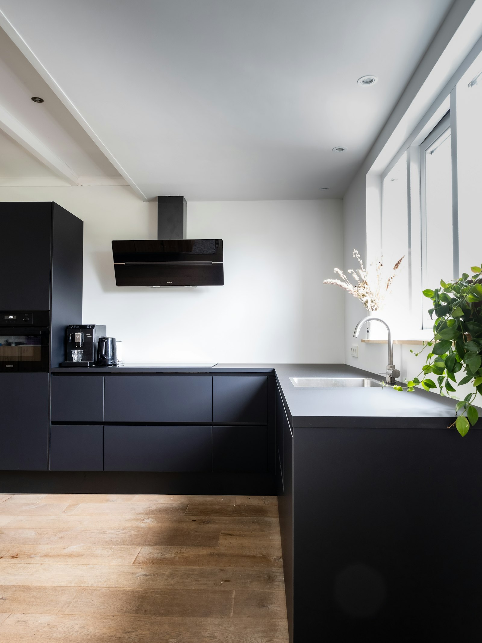 Matte black handle-free kitchen in a bright room