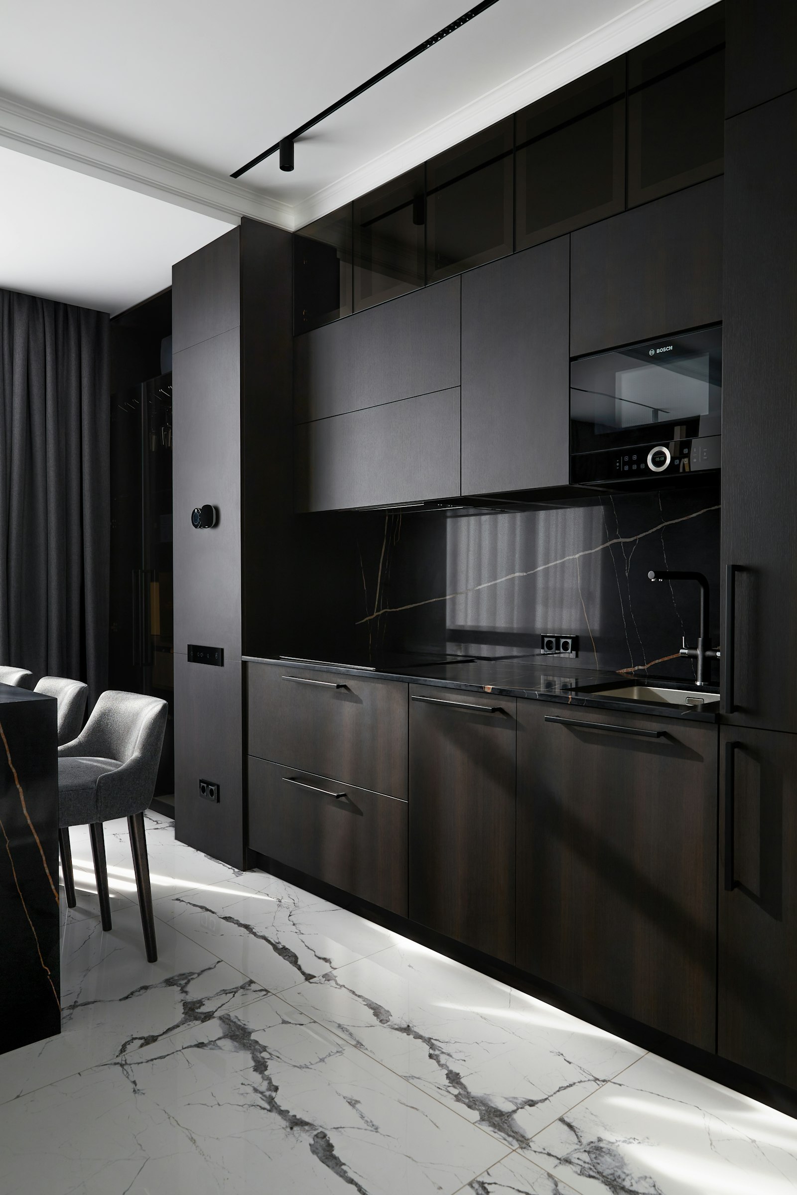 Dark kitchen with book-matched marble floor and worktops